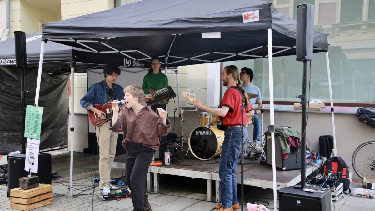 Eine kleine Bühne mit Zeltdach und darauf vier Musiker und eine Sängerin mit Mikro