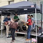Eine kleine Bühne mit Zeltdach und darauf vier Musiker und eine Sängerin mit Mikro