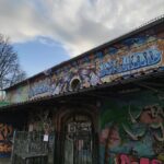 Die Fassade des Clubs Conne Island mit vielen Graffittis, im Hintergrund blauer Himmel und weiße Wolken.