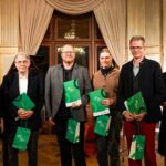 Sechs weiße Menschen, drei Frauen und drei Männer, alle schick gekleidet. Fünf Menschen halten eine grüne Urkunde und grüne Taschen in der Hand mit der Aufschrift: Kultur Tourismus Sachsen.