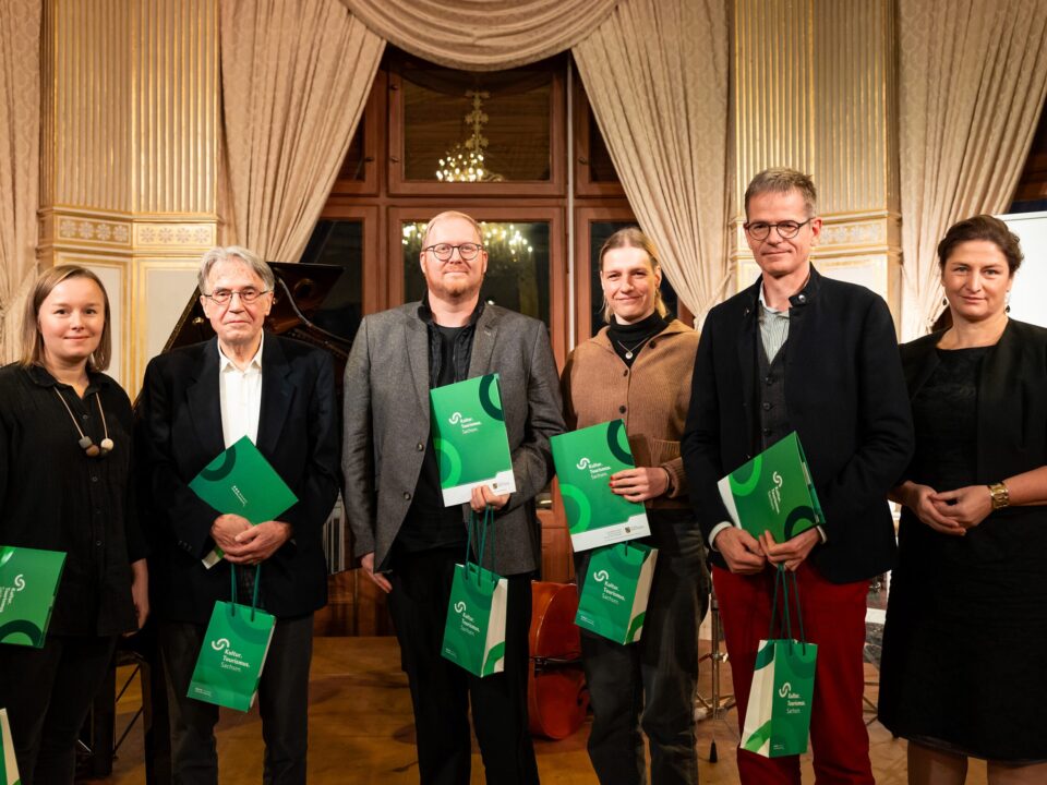 Sechs weiße Menschen, drei Frauen und drei Männer, alle schick gekleidet. Fünf Menschen halten eine grüne Urkunde und grüne Taschen in der Hand mit der Aufschrift: Kultur Tourismus Sachsen.