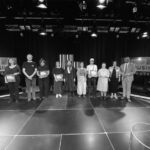 Eine Gruppe Menschen auf einer Bühne, vier von ihnen halten Urkunden in der Hand. Im Hintergrund die Schrift: Wettbewerb Popmusik Sachsen.